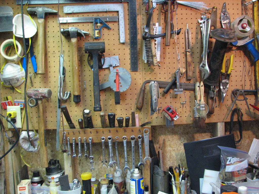 A pegboard workbench with hammers, wrenches, squares and pliers hung in rows